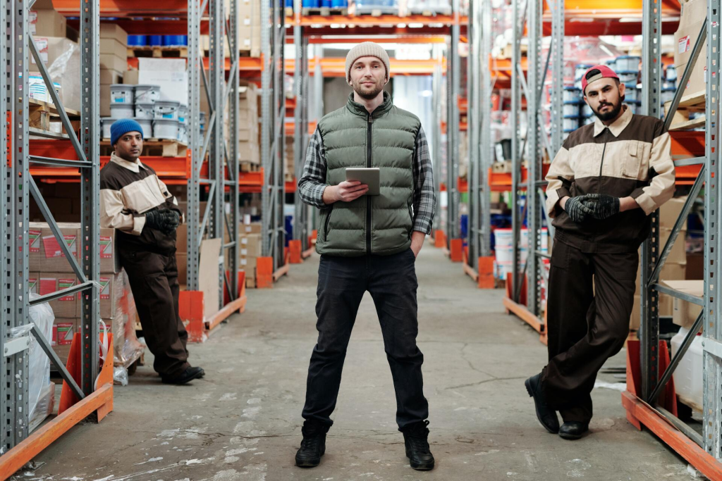 Three men standing in a warehouse holding a tablet