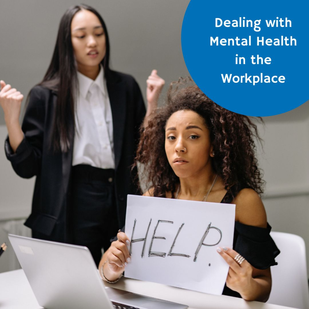 A woman sitting at a desk holding a sign that says help